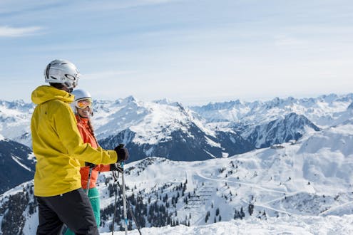 Ein Mann und eine Frau blicken bei ihrem Skikurs mit einer der örtlichen Skischulen in Schruns über das traumhafte Bergpanorama des Montafons.