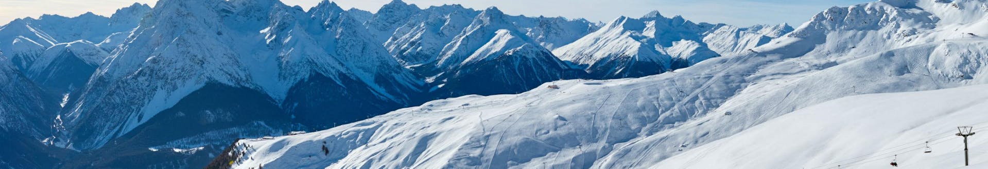 Ein herrliches Panorama über die Skipisten im schweizer Skigebiet Scuol - Motta Naluns, wo örtliche Skischulen eine Reihe an Skikursen anbieten.