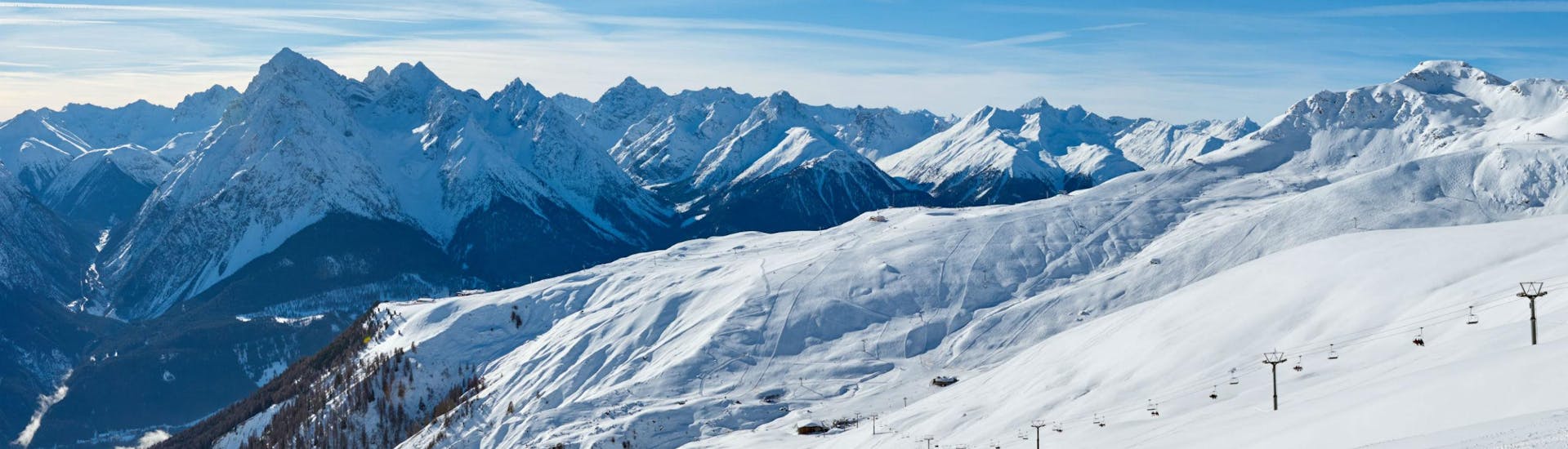 Ein herrliches Panorama über die Skipisten im schweizer Skigebiet Scuol - Motta Naluns, wo örtliche Skischulen eine Reihe an Skikursen anbieten.