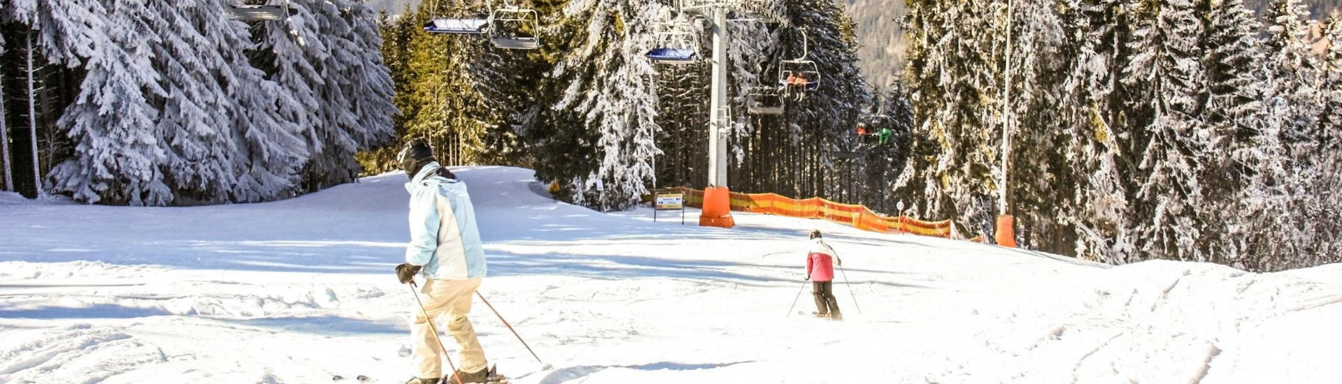 Two skiers are skiing down one of the ski slopes in the ski resort of Zauberberg-Hirschenkogel, where visitors can book ski lessons with the local ski schools.