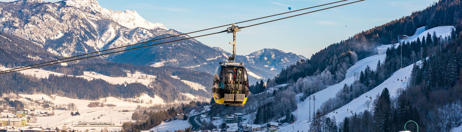 Eine Gondel hängt suspendiert über der Stadt Schladming, einem beliebten Ort für Skischulen die in der Region Ski Amadé Schladming Dachstein ihre Skikurse anbieten.