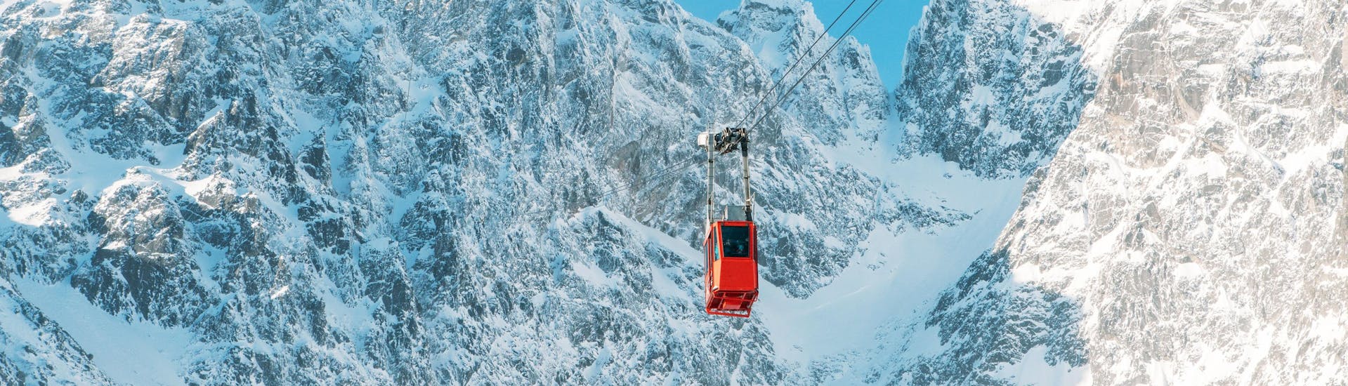 Eine rote Gondel, die auf einen Gipfel im Skigebiet Tatranská Lomnica fährt, wo die örtlichen Skischulen ihre Skikurse anbieten.