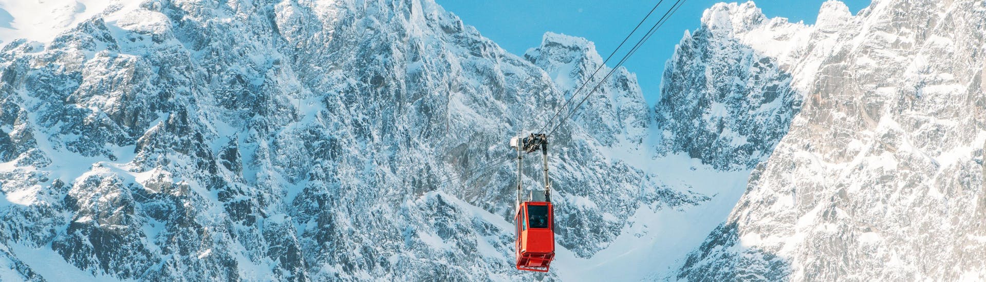 A red gondola going up to a peak in the ski resort Tatranská Lomnica, where local ski schools offer their ski lessons.