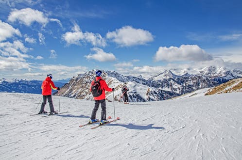 Skiers are enjoying the stunning panorama of Val di Fiemme, where local ski schools offer their ski lessons.