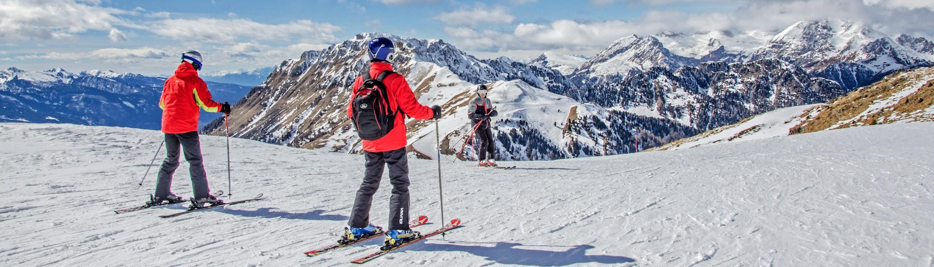 Skifahrer auf dem Gipfel der Berge mit Blick auf das Skigebiet.
