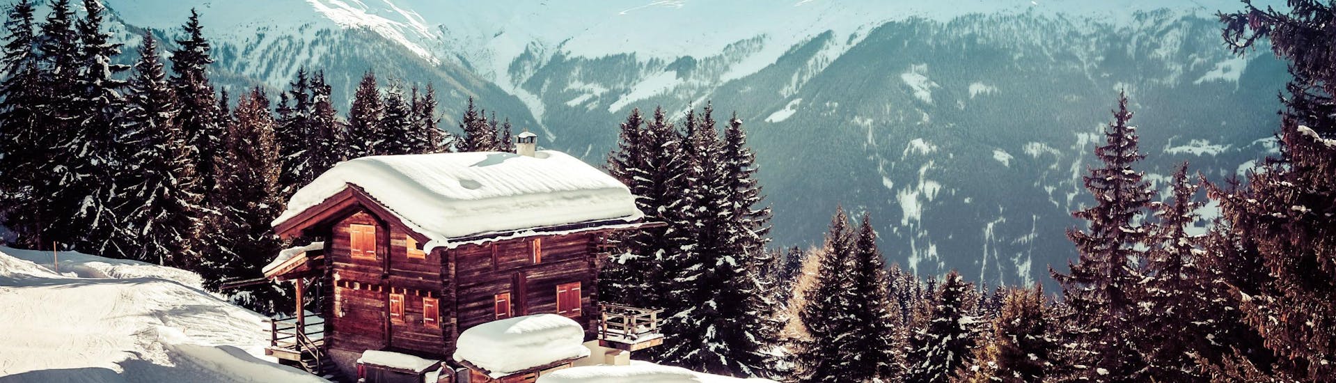 An image of a lone snowboarder boarding past a small mountain hut in the swiss ski resort of Verbier, where where visitors can learn to ski during their ski lessons provided by local ski schools.