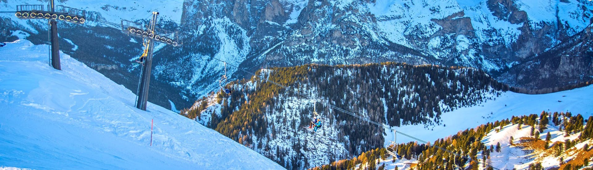 Eine Gruppe Skifahrer fährt mit dem Sessellift den Berg hinauf um dort mit dem von einer örtlichen Skischule organisierten Skikurs in Vigo di Fassa zu beginnen.