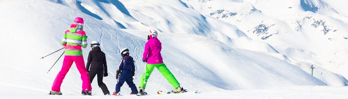 ski-school-vogel-ski-center_SEM-Resort-Hero Eine Familie fährt die Pisten des Vogel Ski Center in Slowenien hinunter, wo die örtlichen Skischulen ihre Skikurse anbieten.