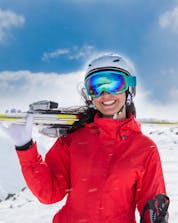 An image of a young woman carrying her skis in La Molina/Masella, a popular place to book ski lessons with one of the local ski schools.