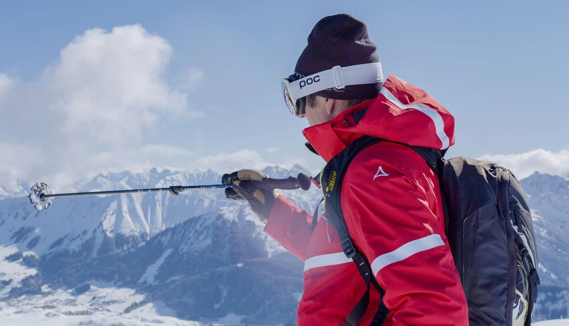 Un maestro di sci della scuola di sci Hirschegg indica il panorama montano con il suo bastone da sci durante una lezione di sci nella Kleinwalsertal.