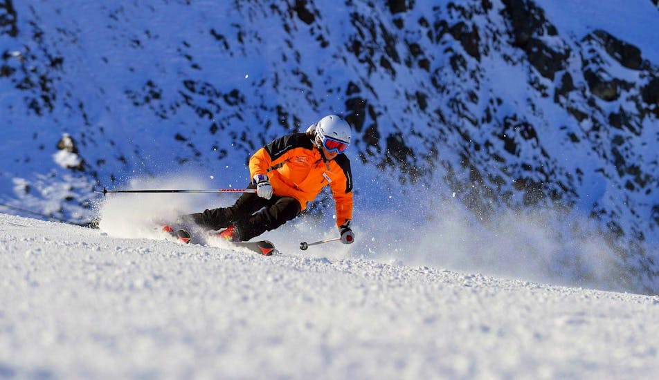 A skier whizzes down the slopes and lets the snow splash while being optimally coached by the ski school Ingrid Salvenmoser.