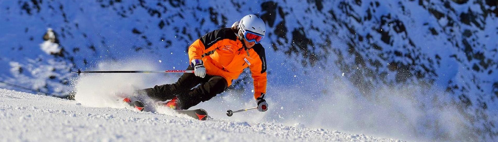 Ein Skifahrer flitzt die Pisten hinunter und lässt dabei den Schnee spritzen, während er optimal von der Skischule Ingrid Salvenmoser betreut wird.