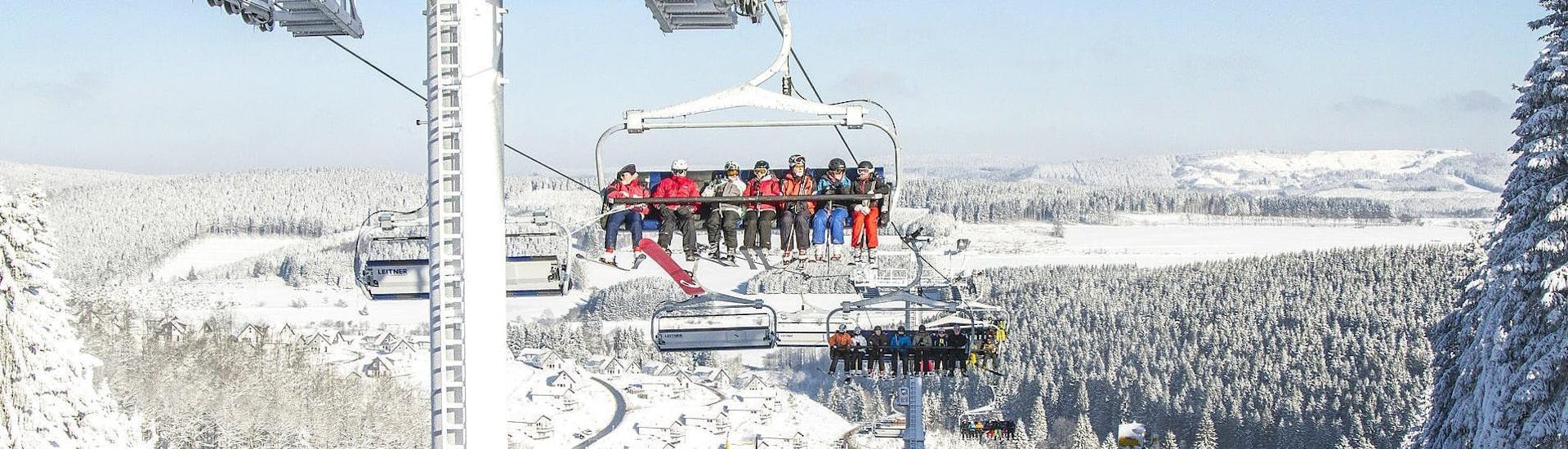Eine Gruppe von Skifahrern fährt mit dem Sessellift den Berg hoch, um Ihren Skikurs mit der Skischule Kahler Asten im Skigebiet Winterberg zu beginnen.