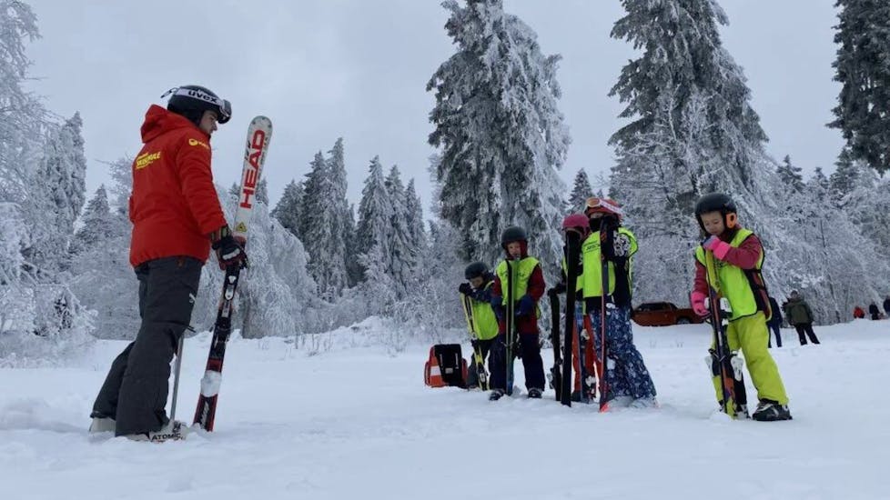 An instructor and kids having fun during their ski lesson at Ski school Sportwelt Oberhof.