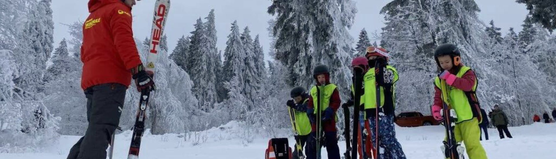Ein Skilehrer und eine Gruppe Kinder hat Spaß während dem Kinder-Skikurs bei der Skischule Sportwelt Oberhof.