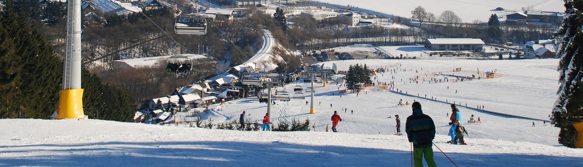 An image of a chair lift carrying skiers up the mountain in the ski resort of Willingen, where local ski schools offer ski lessons to skiing enthusiasts of all levels.