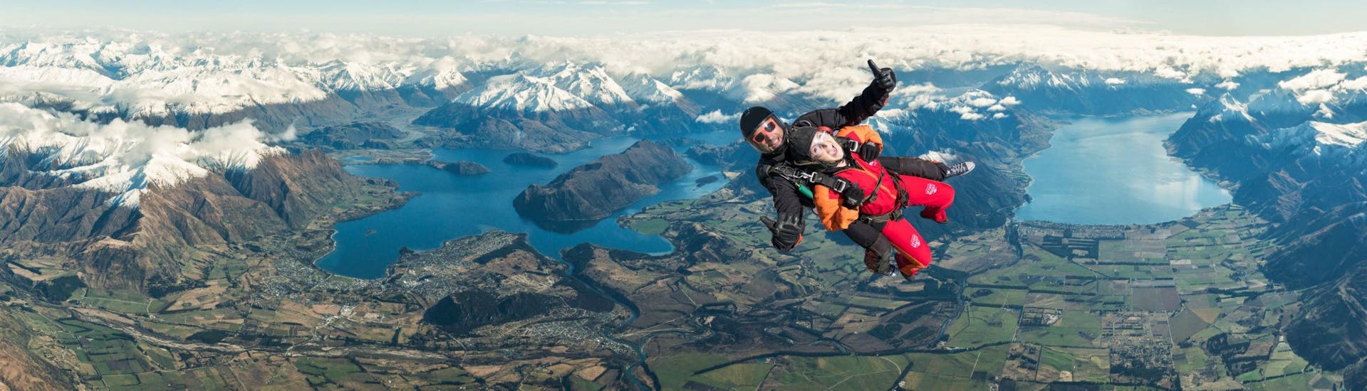 A tandem master from Skydive Wanaka and his passenger are in the middle of their free fall high above the spectacular mountainscape around Lake Wanaka.