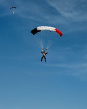 A man can be seen skydiving near Paris with a French flag as his parachute. 