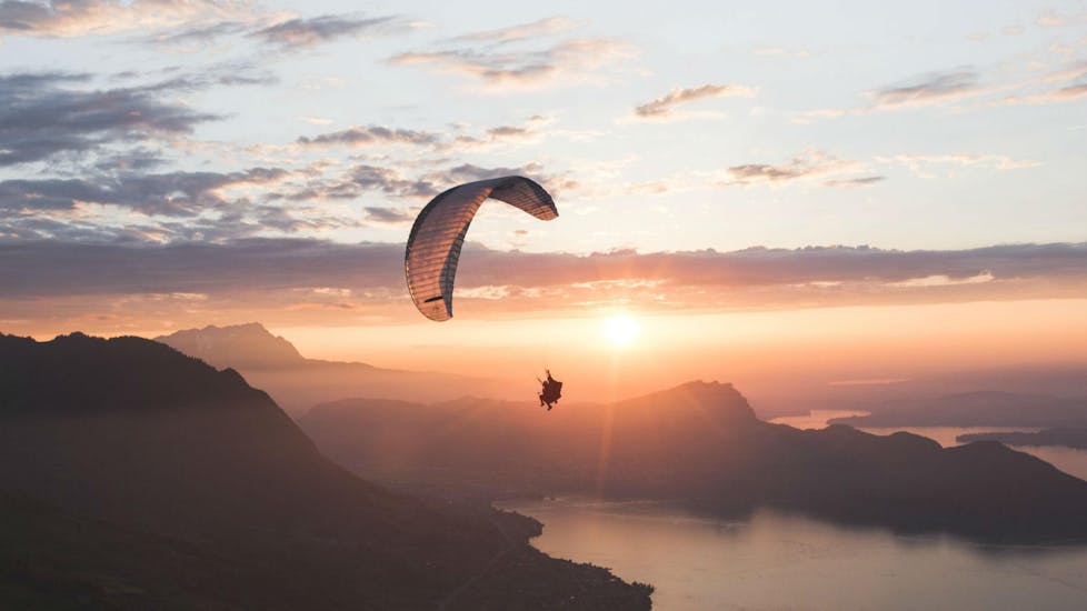 Two people are paragliding during sunset