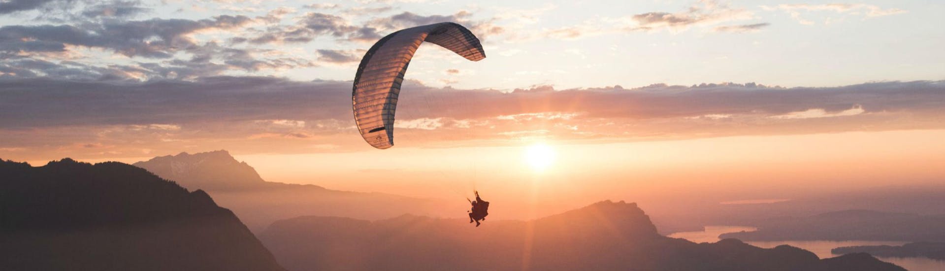 Zwei Personen fliegen bei Sonnenuntergang mit dem Gleitschirm