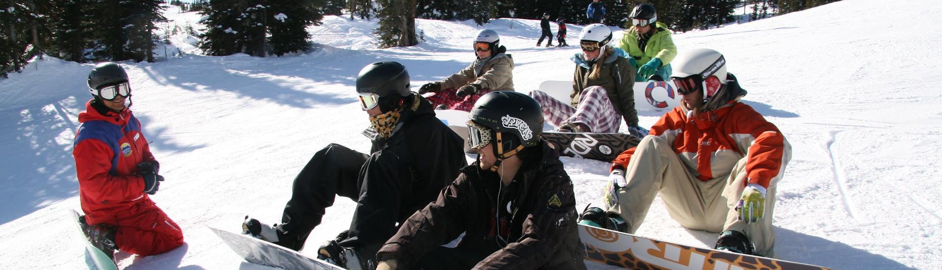 Groep snowboarders die samen plezier hebben tijdens een snowboardles voor beginners