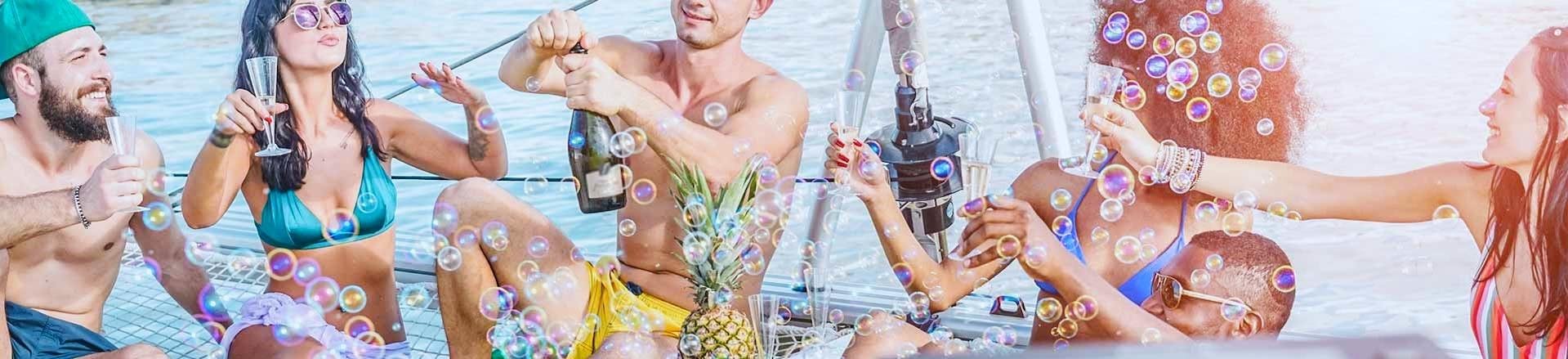 A group of participants having fun surrounded by bubbles and drinks on a party boat in Mykonos during an activity with Mykonos Boat Club.