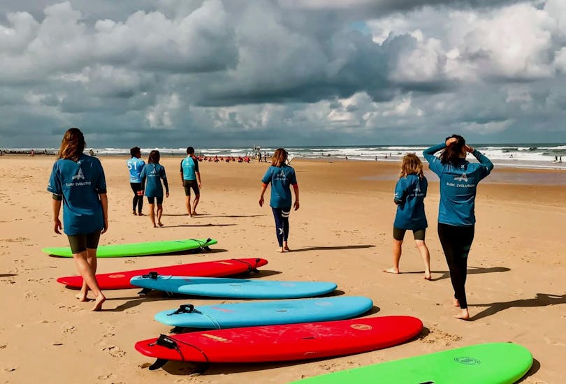 Un groupe de surfeurs s'échauffe sur la plage tout en évaluant les vagues lors d'un cours de surf avec Surf Evolution Seignosse. 