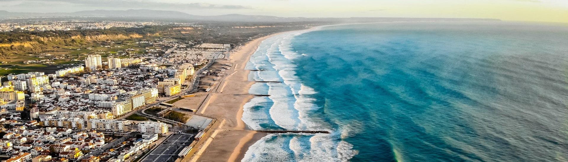 An aerial view of the beach of Costa da Caparica, a popular spot for surfing lessons near Lisbon.