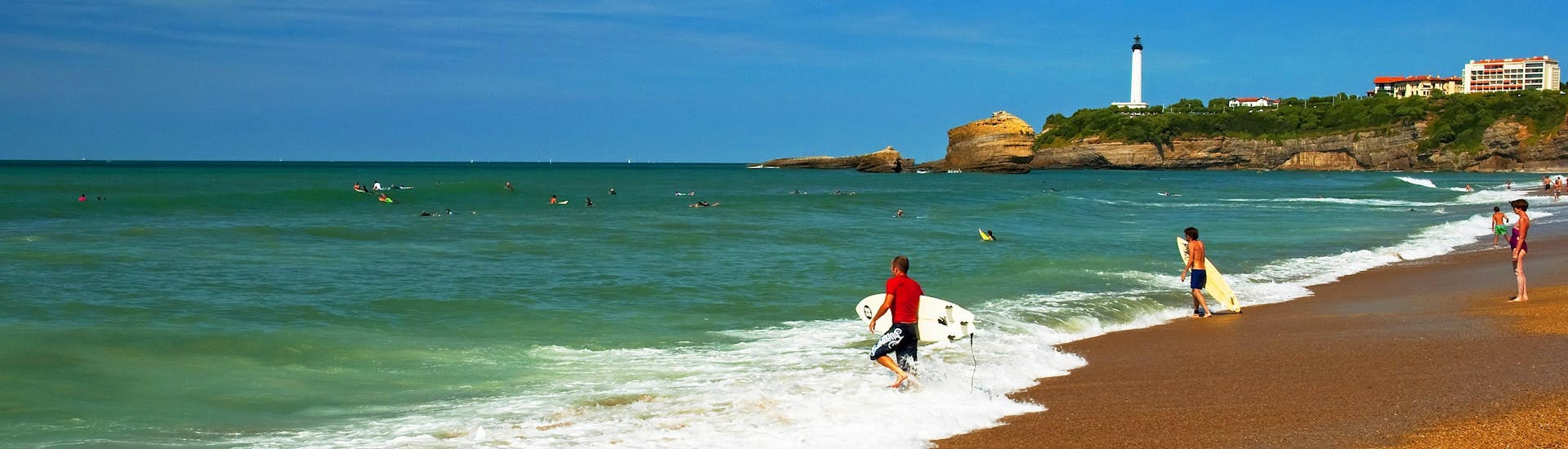 A young woman surfing in the clear blue waters of the surfing and SUP hotspot of La Côte des Basques.