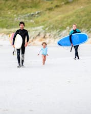A happy family is walking along the beach as they enjoy a day of surfing in Galicia.