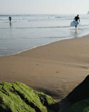 Deux jeunes hommes marchent sur la plage avec l'eau et les vagues font du surf à Hendaye.