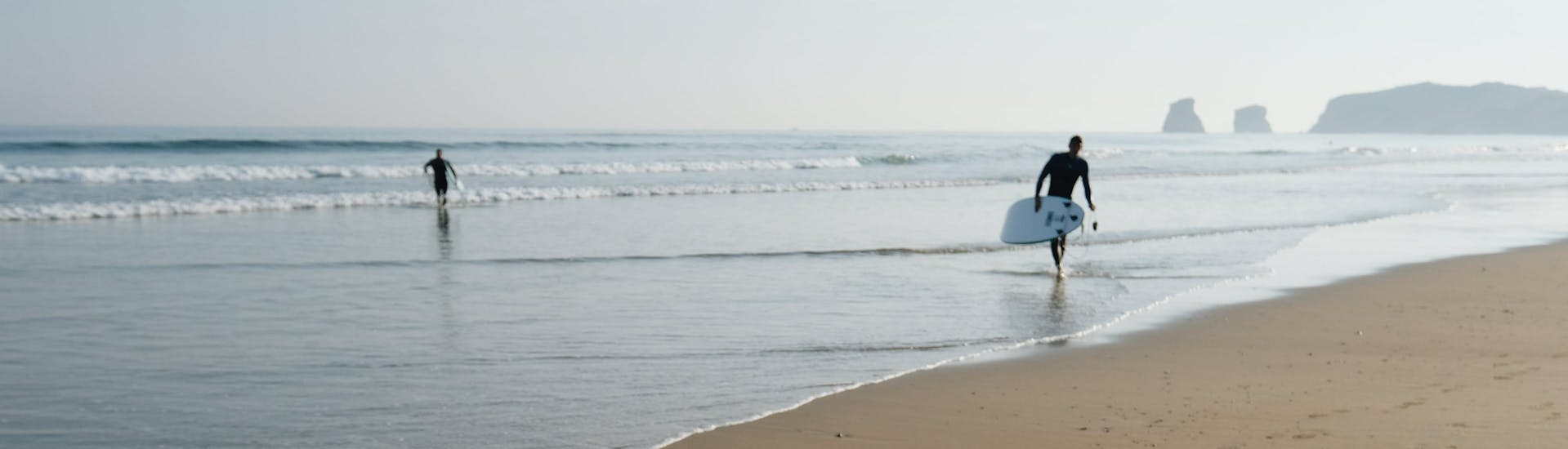 Un surfeur marche sur la plage d'Hendaye au petit matin, un des meilleurs endroits pour prendre des cours de surf dans le Pays basque.