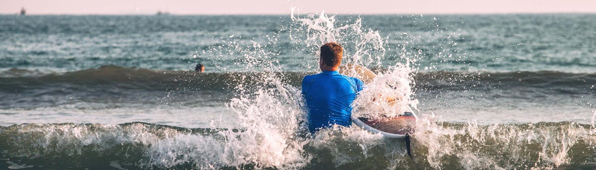 surfing-hossegor_SEM-Resort-Hero A young man is wading through the water with his board while surfing in Hossegor.