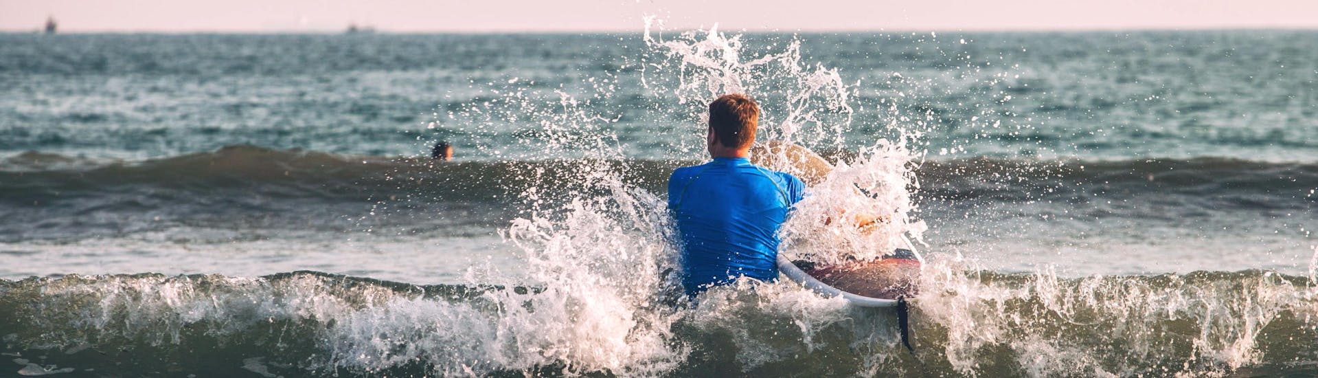 Un jeune homme patauge dans l'eau sur sa planche pendant une sortie surf à Hossegor.