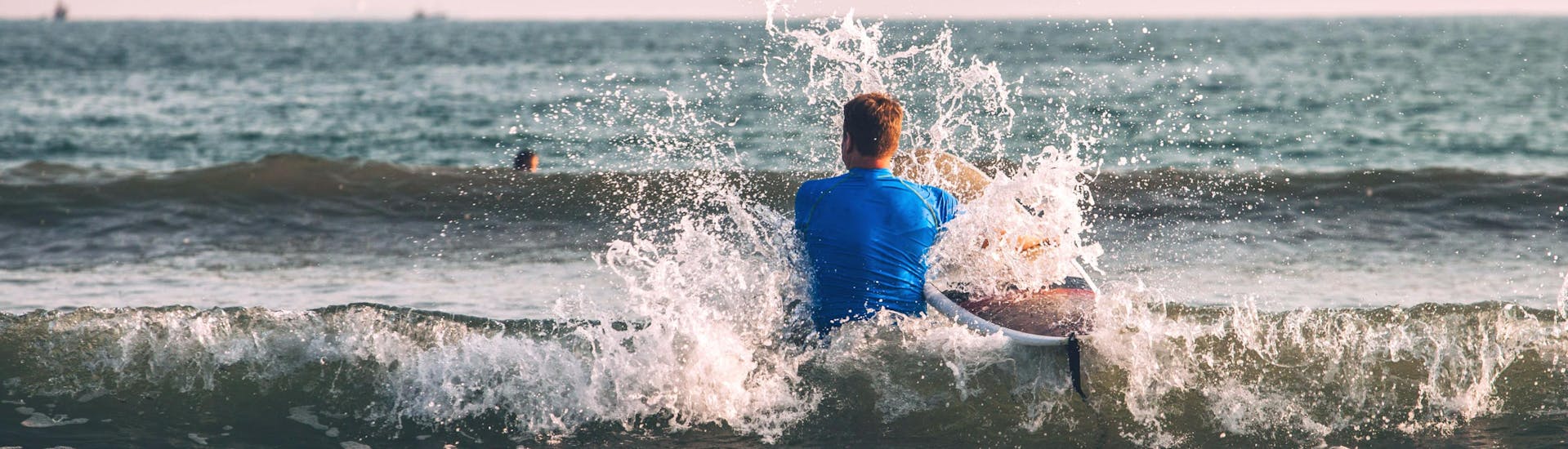 Un jeune homme patauge dans l'eau sur sa planche pendant une sortie surf à Hossegor.