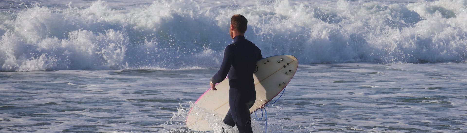 Ein Surfer trägt beim Surfen in Mimizan sein Brett ins Meer.