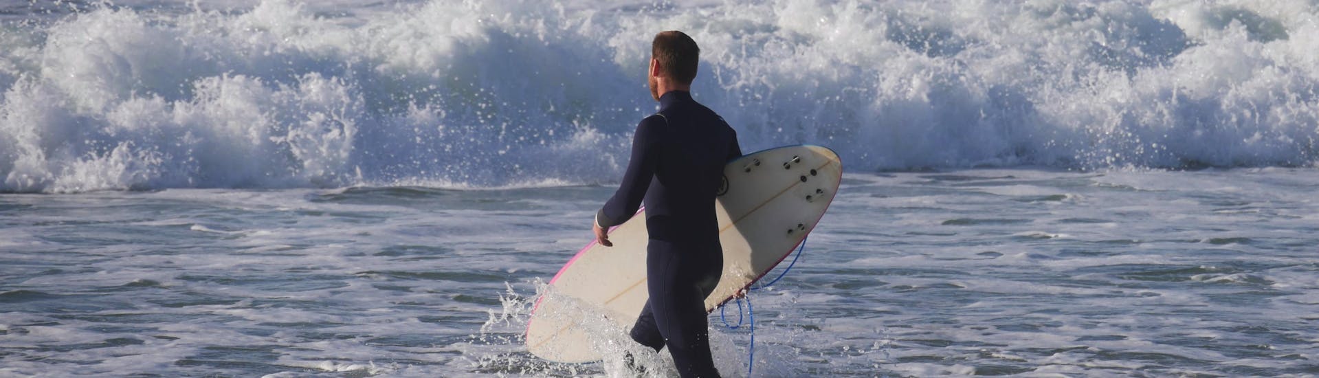 Ein Surfer trägt beim Surfen in Mimizan sein Brett ins Meer.