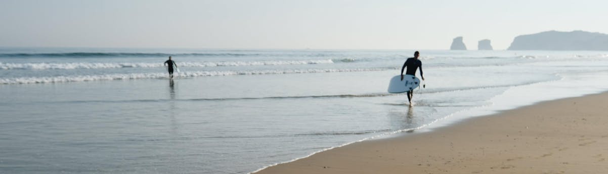 surfing-plage-hendaye_SEM-Resort-Hero A surfer is walking on the beach of Hendaye in the early morning, one of the best places to take surfing lessons in the Basque Country.