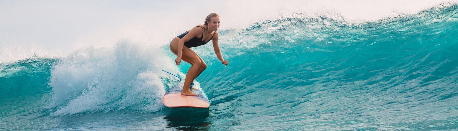 Une jeune femme fait du surf dans la destination de vacances Benagil.