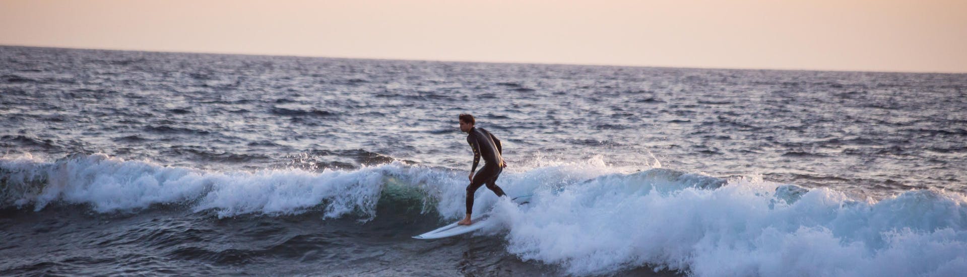 Ein Surfer reitet eine Welle in Playa de las Américas, einem großartigen Ort zum Surfen auf Teneriffa.