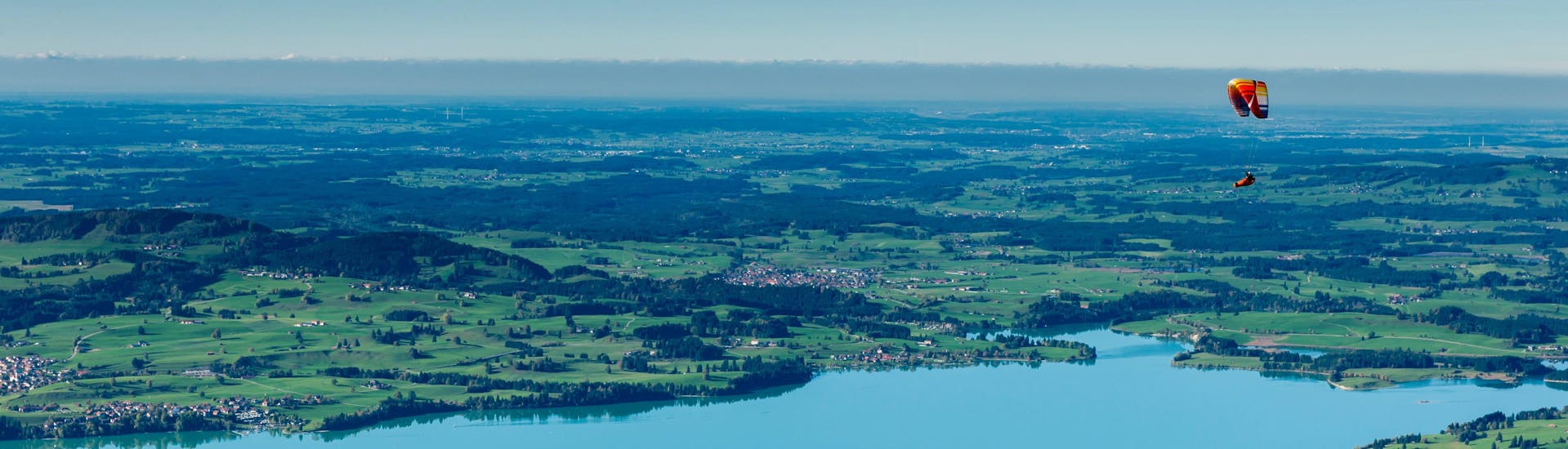 Un parapentiste est émerveillé par le paysage lors d'un vol en parapente biplace dans la célèbre destination de parapente Schwangau - Tegelberg.