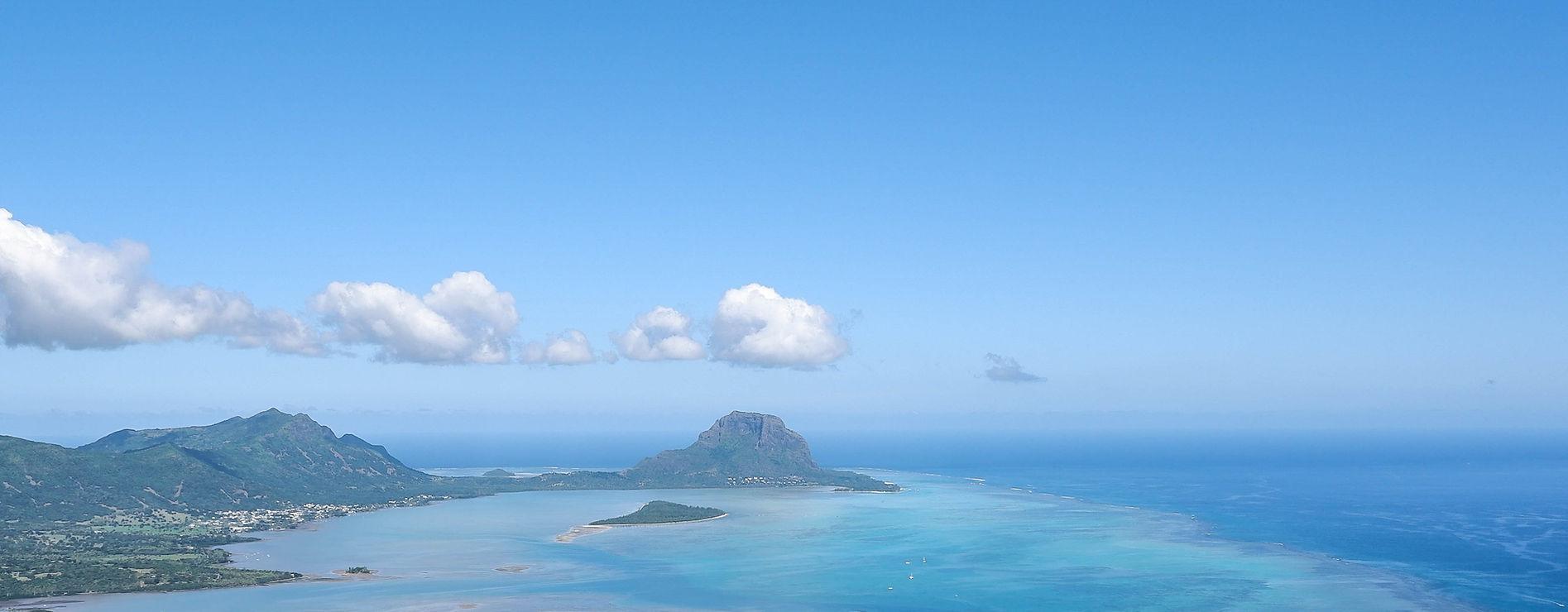 Paysage de l'île Maurice avec la montagne Le Morne Brabant, des lagunes turquoise et un ciel bleu clair.