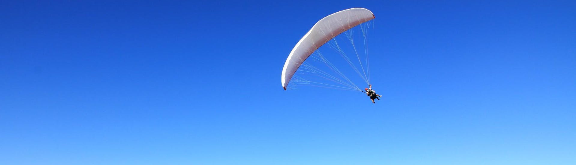 Two people taking a thermal paragliding flight.