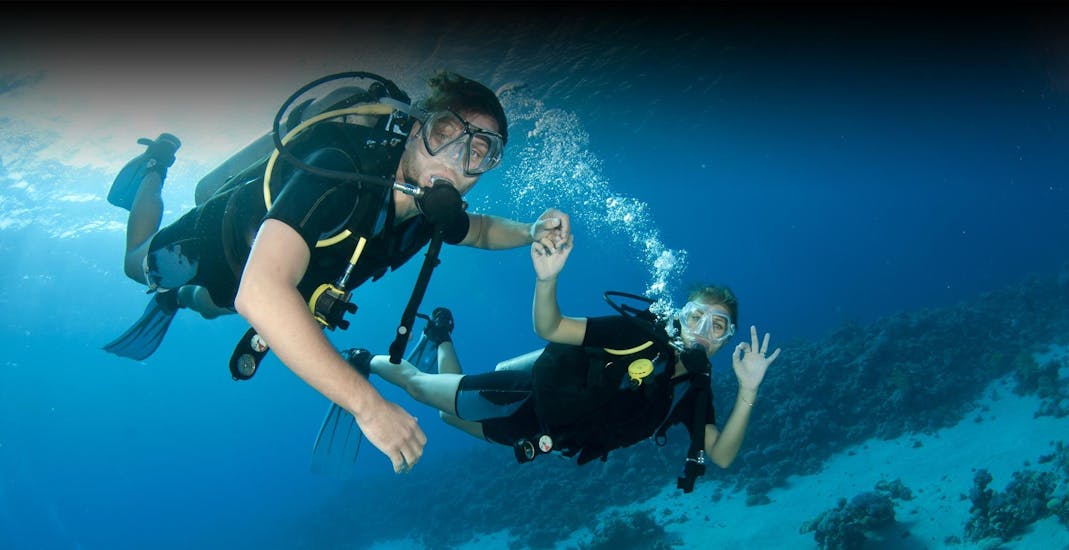 Twee mensen die duiken en één persoon geeft het “I am okay” teken tijdens een activiteit van Triton Scuba Club Halkidiki.