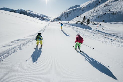 Adultos y niños esquiando en la estación de esquí de Turracher.