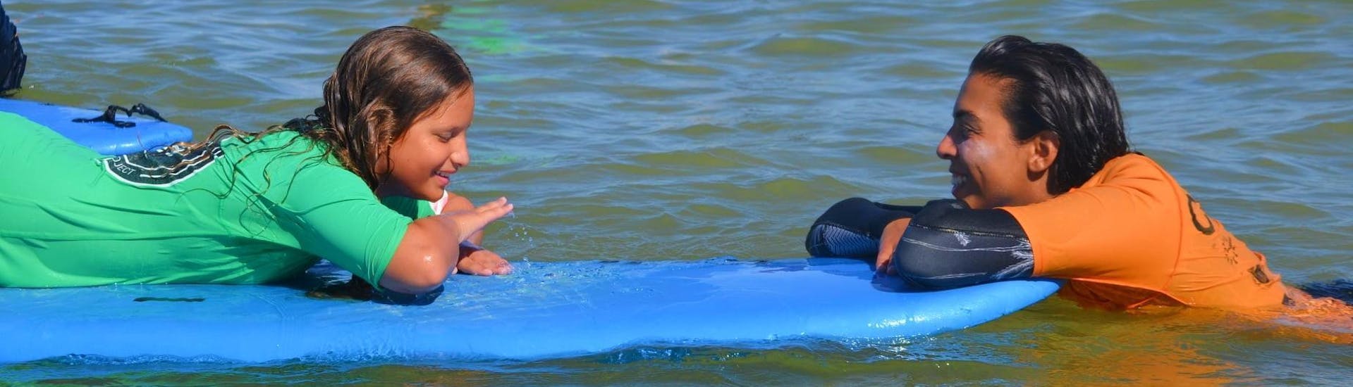 Eine Surflehrerin von Vilamoura Surf Project erklärt einem Kind die richtige Surftechnik.