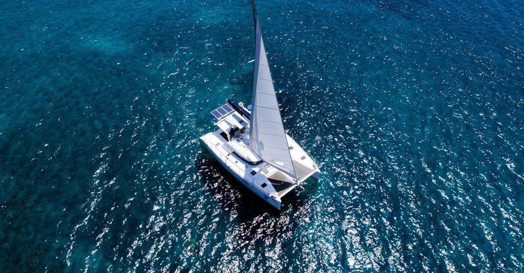 A catamaran on the beautiful sparkling water of the Cyclades from Volcano Yachting Santorini.