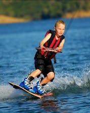 A boy is Wakeboarding at Praia de Armação de Pêra with the help of an experienced instructor from Moments Watersports Algarve.