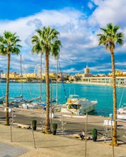 Una vista del puerto con la ciudad y el océano donde se pueden hacer actividades de deportes acuáticos en Málaga.