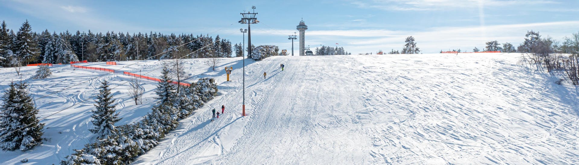 An image of a chair lift carrying skiers up the mountain in the ski resort of Willingen, where local ski schools offer ski lessons to skiing enthusiasts of all levels.